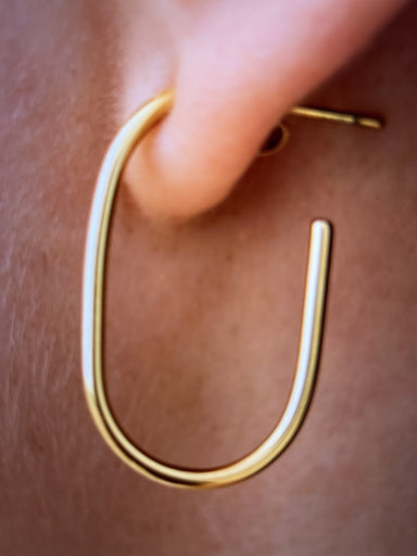 Gold hoop earring worn on a person's ear