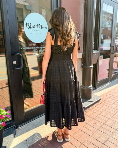 Woman in a black dress standing outside a store with 'Blue Moon' branding.