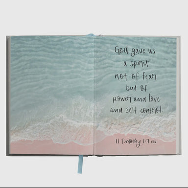 Open book with ocean scene and inspirational quote on a white background