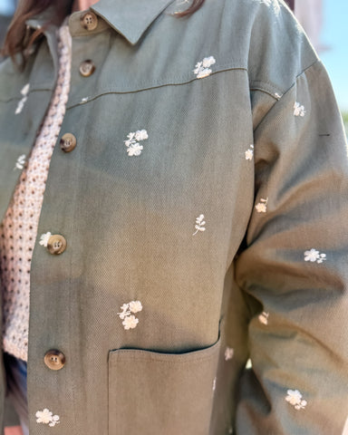 Green jacket with floral patterns and buttons on a blurred background