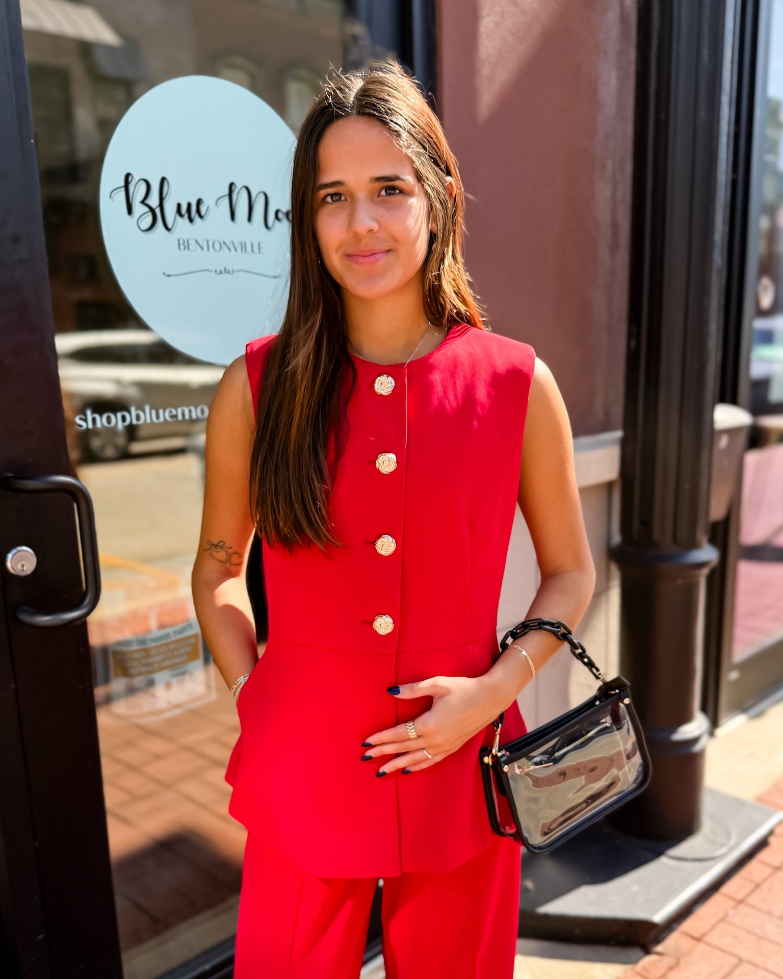 Woman in a red outfit standing outside a store with 'Blue Moon' branding.