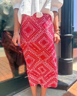 Woman wearing a red and white bandana print cotton midi skirt paired with a white blouse for a classic game day inspired outfit.