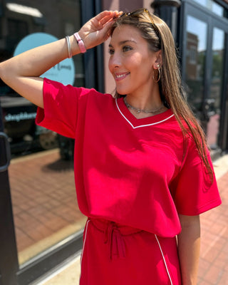 Red modal varsity v-neck top by Rae Mode, shown on model