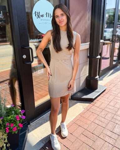 Woman in a beige dress standing outside a store with 'Blue Moon' branding.