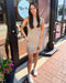 Woman in a beige dress standing outside a store with 'Blue Moon' branding.