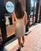 Woman in a beige dress standing outside a store with 'Blue Moon' branding.