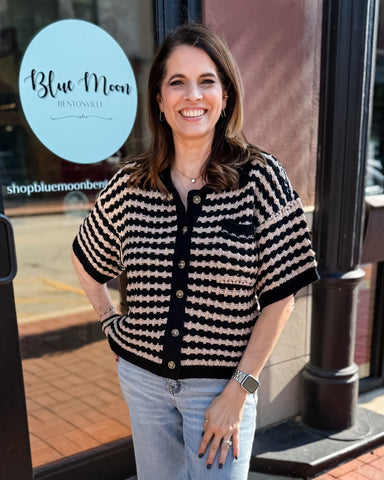 Woman wearing a black and white striped shirt standing in front of a store with 'Blue Moon' branding.