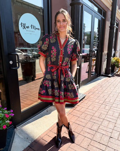 Woman in a floral dress standing outside a store with 'Blue Moon' branding.
