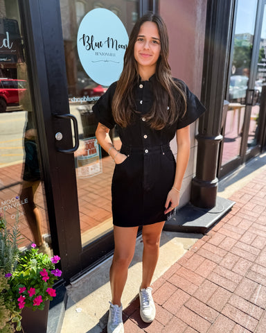 Woman in a black outfit standing outside a store with 'Blue Moon' branding.