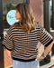 Woman wearing a black and beige striped sweater with a blurred background