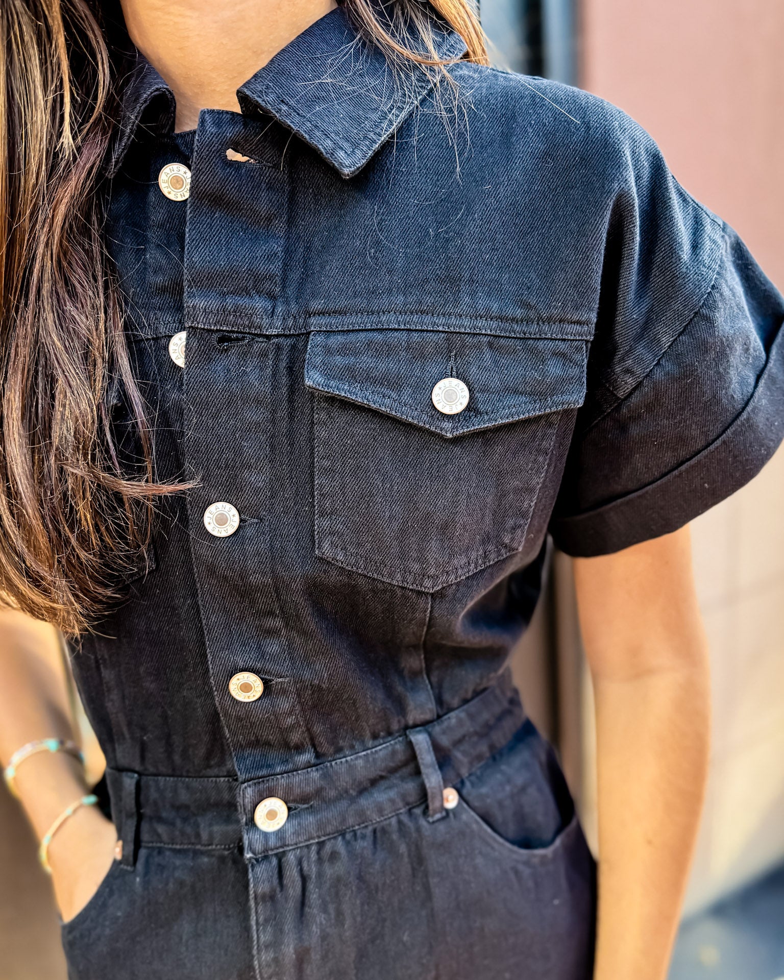 Denim jumpsuit with button details worn by a person, blurred background