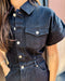 Denim jumpsuit with button details worn by a person, blurred background