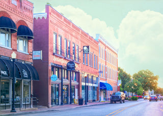 Street view of a small town with brick buildings and cars on a clear day