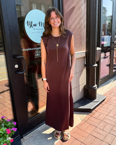 Woman in a brown dress standing outside a store with 'Blue Moon' branding.
