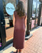 Person wearing a brown dress standing outside a store with 'Blue Moon Boutique' sign.