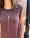 Person wearing a long gold necklace with a star pendant on a blurred background