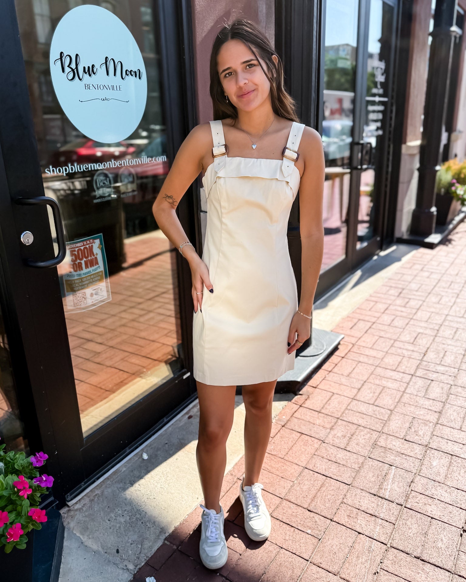 Woman in a white dress standing outside a store with 'Blue Moon' branding.