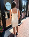Woman in a white dress standing outside a store with 'Blue Moon' branding.