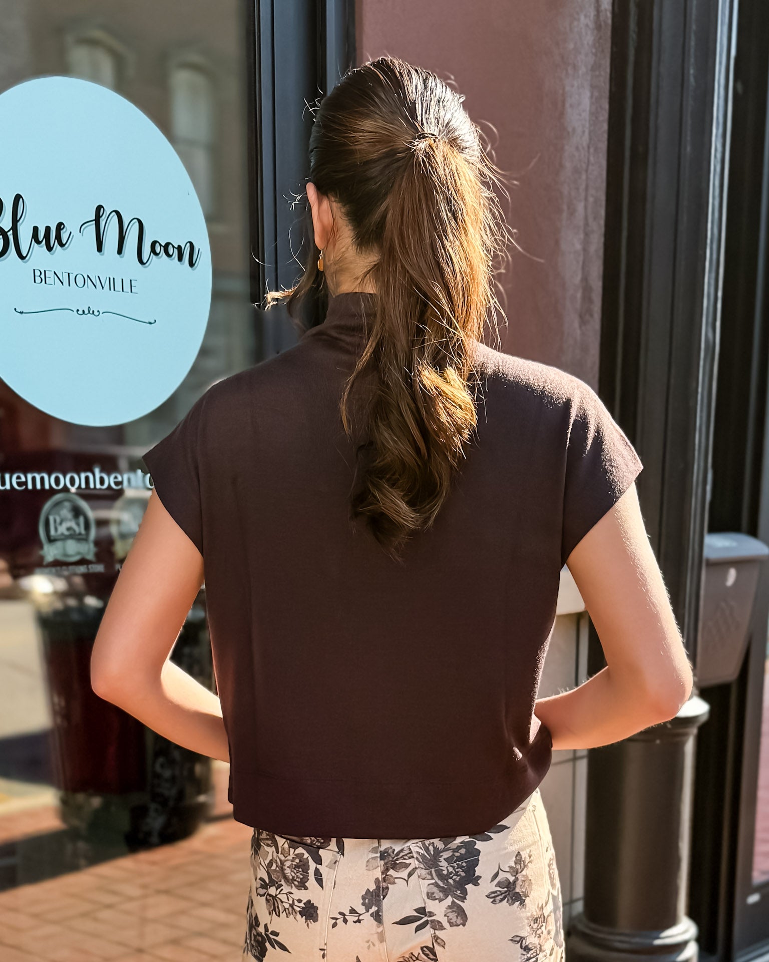 Woman standing outside a building with 'Blue Moon' branding.