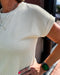 Person wearing a light-colored sleeveless top with a blurred background