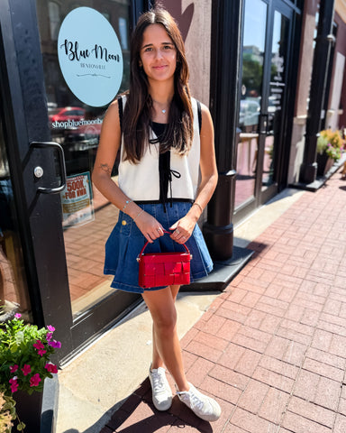 Woman holding a red handbag in front of a store with 'Blue Moon' sign.