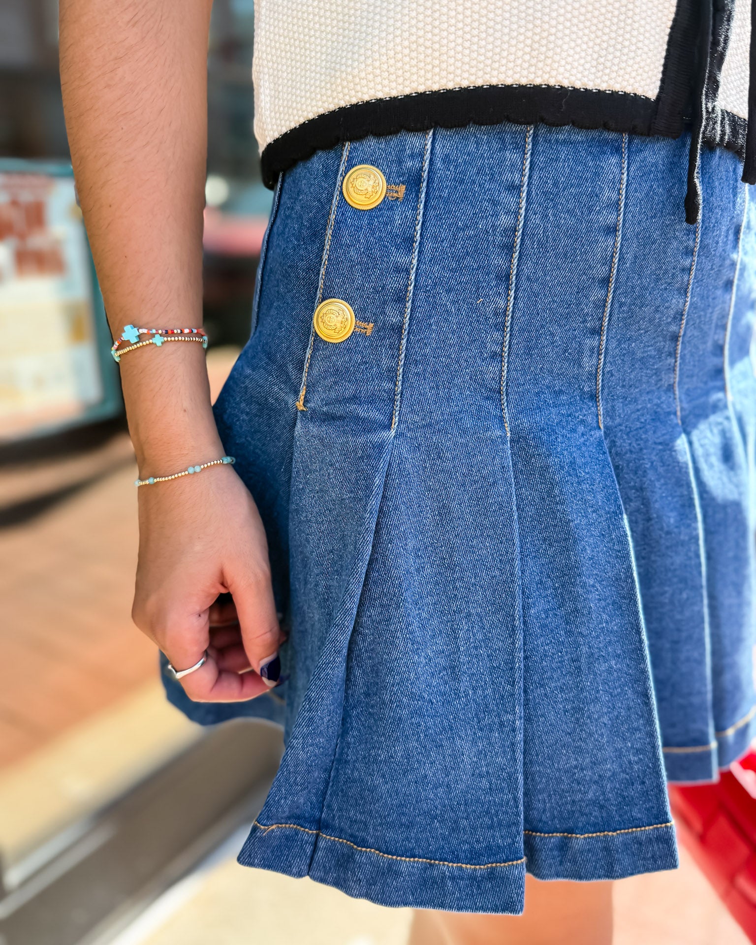 Close-up of a person wearing a blue denim skirt with gold buttons.