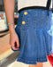 Close-up of a person wearing a blue denim skirt with gold buttons.
