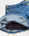 Close-up of a blue denim skirt with yellow buttons on a white background