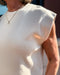 Close-up of a person wearing a light-colored sleeveless top with a blurred background