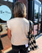 Person with a checkered bag walking past a store named 'Blue Moon'.