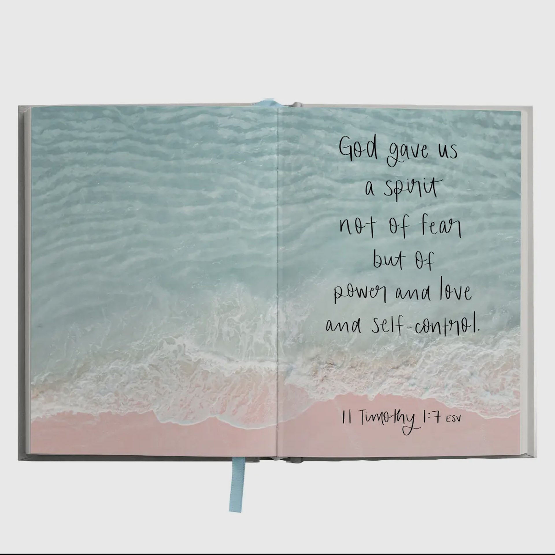 Open book with ocean scene and inspirational quote on a white background