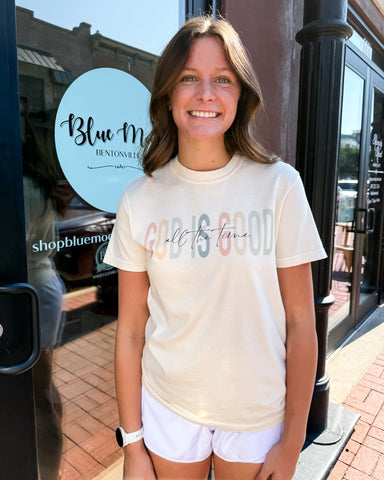 Woman wearing a 'Good is Good' t-shirt in front of a store with a Blue Moon Bendon Hills sign.