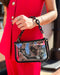 Person holding a black handbag with a reflective surface, wearing a red outfit.