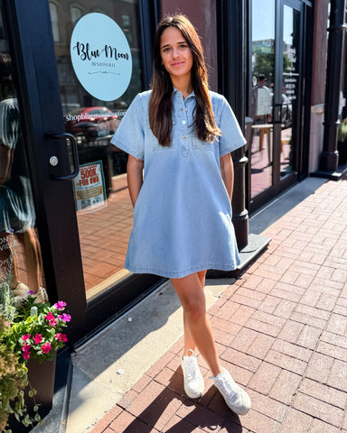 Woman in a light blue dress standing outside a store with 'Blue Moon' branding.