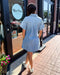 Person wearing a light blue dress standing outside a store with 'Blue Moon' branding.