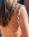 Brown crochet top worn by a person with blurred background
