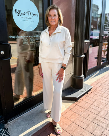 Woman in a white outfit standing outside a store with 'Blue Moon' branding.