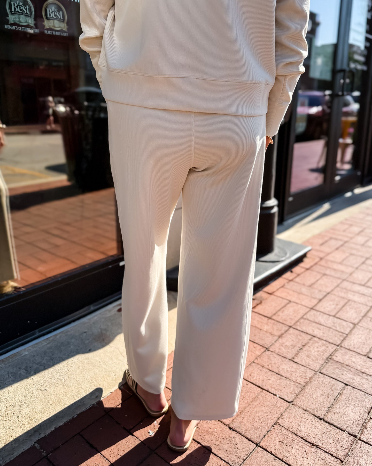 Person wearing a white outfit standing on a sidewalk