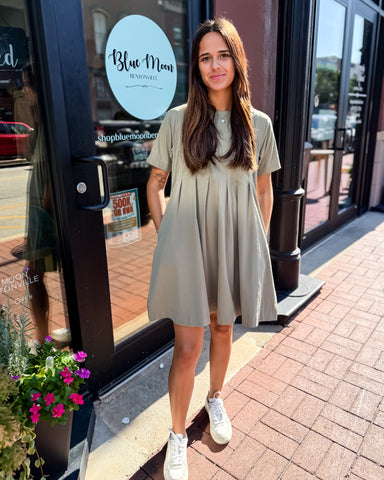 Woman in a light green dress standing outside a store named 'Blue Moon'.