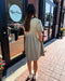 Woman in a beige dress standing outside a store with 'Blue Moon' branding.