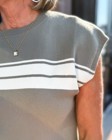 Person wearing a gray sweater with white stripes, blurred background