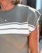 Person wearing a gray sweater with white stripes, blurred background