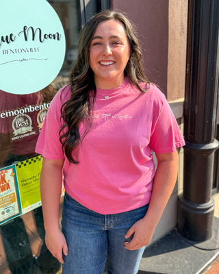 Model wearing a pink Dear Heart Christian graphic t-shirt featuring He Holds All Together front artwork and bow graphics inspired by Colossians 1:17.