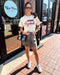 Woman wearing an Arkansas Razorbacks t-shirt and leopard print skirt standing on a sidewalk.