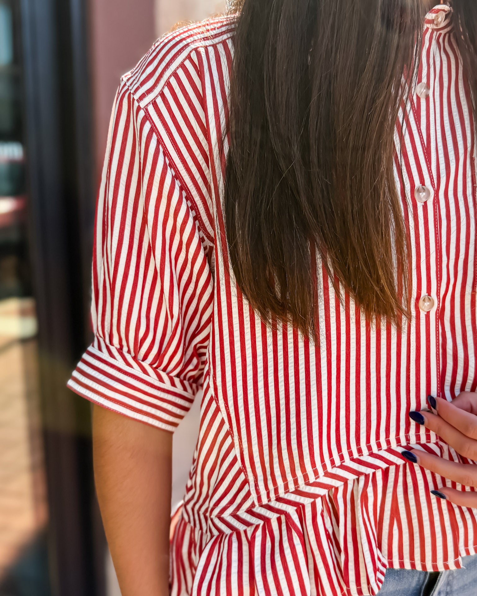Person wearing a red and white striped shirt with a blurred background