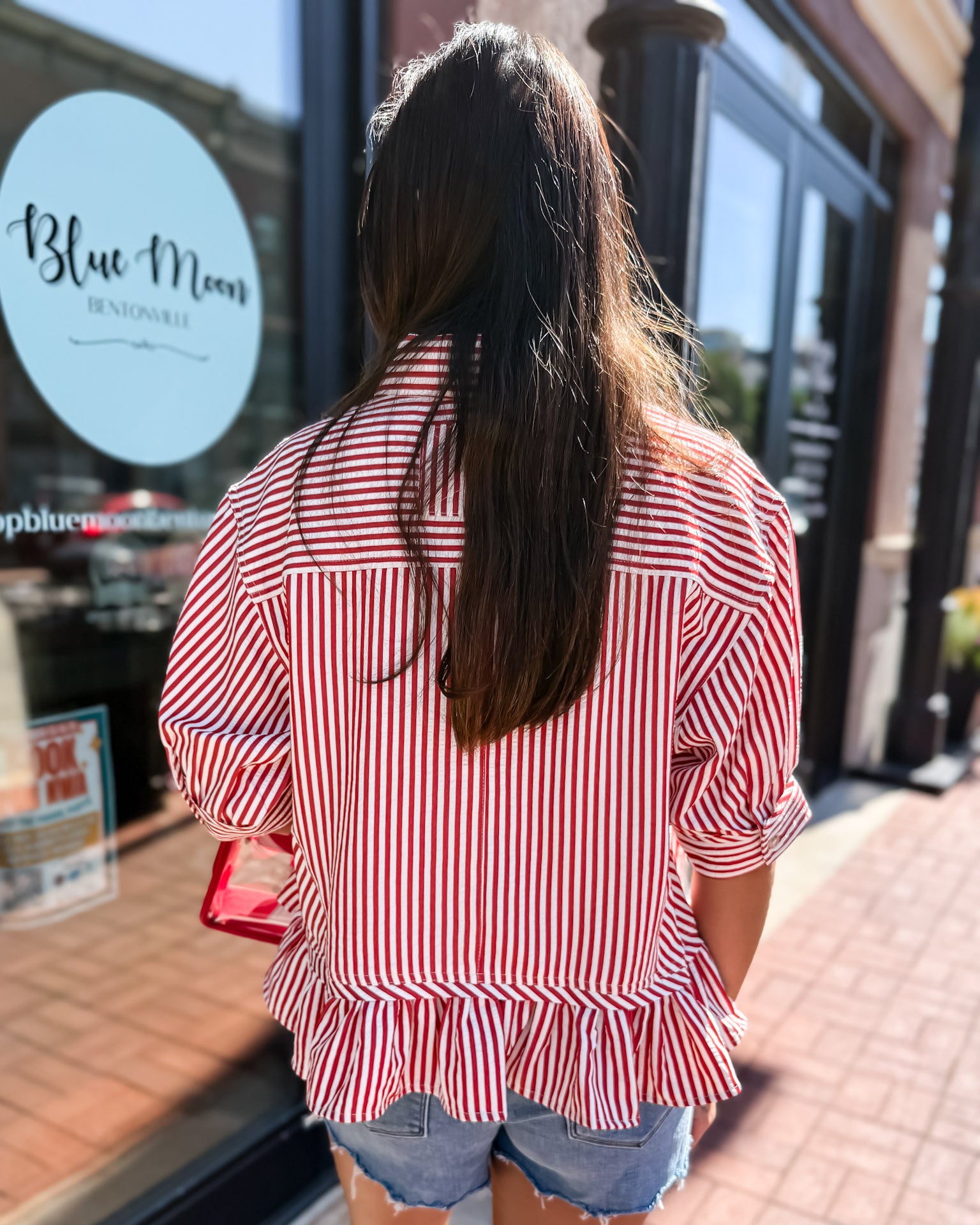 Person wearing a red and white striped shirt in front of a store with 'Blue Moon' branding.