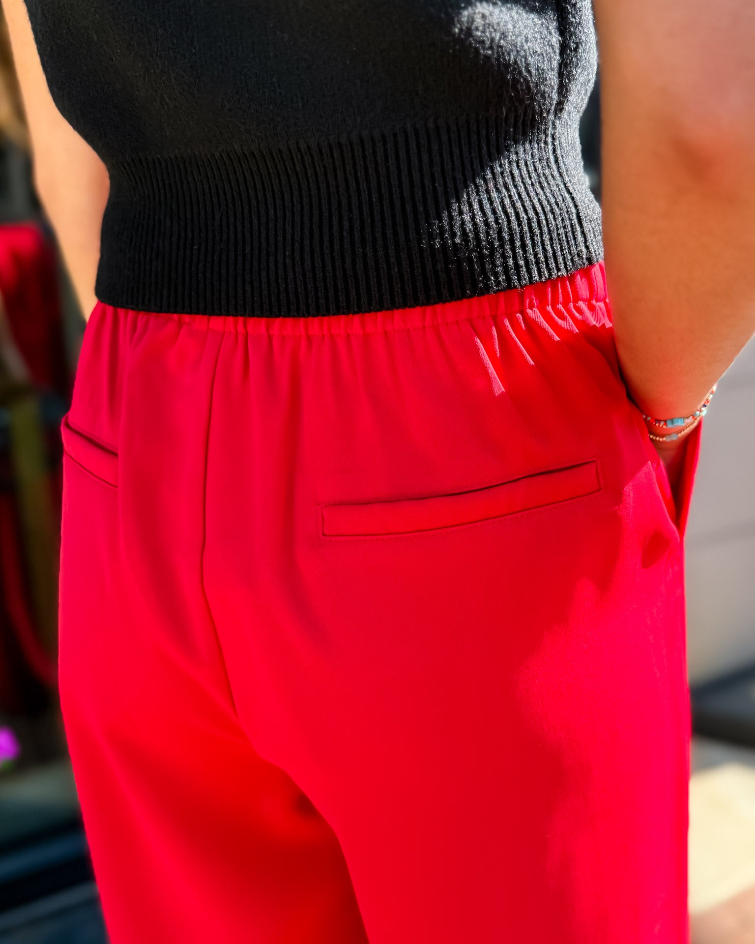 Person wearing a black top and red pants with a blurred background