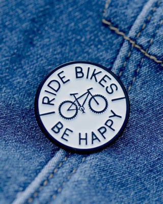 Black and white Ride Bikes Be Happy enamel bicycle lapel pin with circular design and rubber clutch backing.