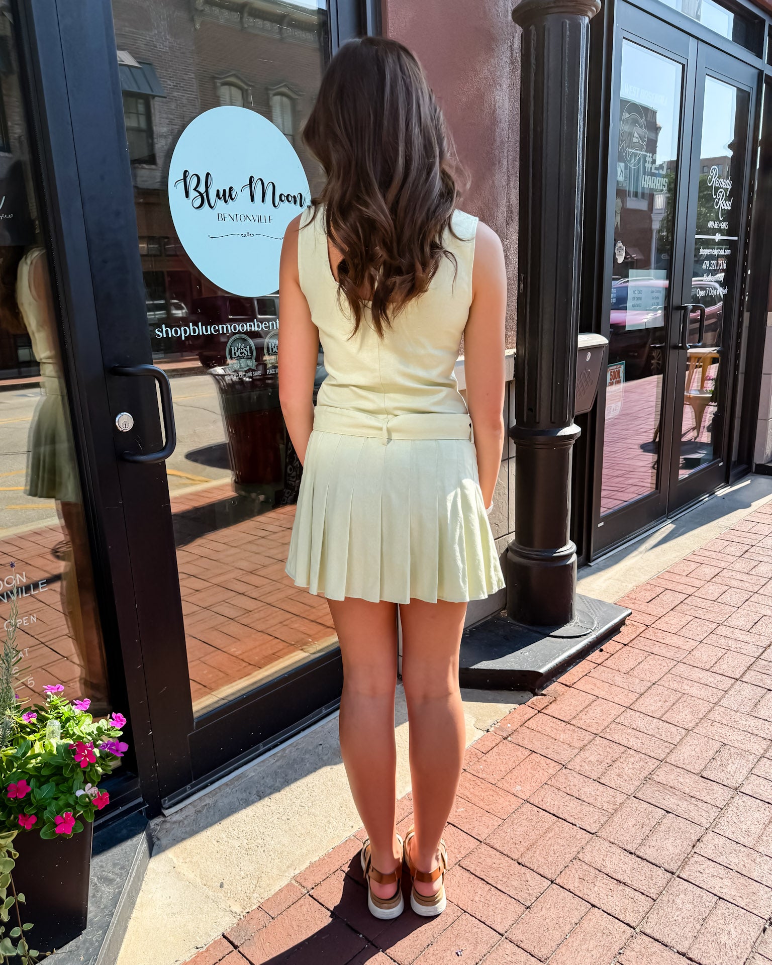 Woman in a light yellow dress standing outside a store with 'Blue Moon' branding.