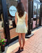 Woman in a light yellow dress standing outside a store with 'Blue Moon' branding.